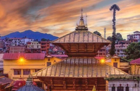 Panoramic view of Pashupatinath Temple complex in Kathmandu showing the golden pagoda roofs, stone shrines, and the sacred Bagmati River ghats under a clear blue sky.