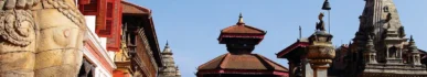 A wide view of the ancient Bhaktapur Durbar Square in Nepal, featuring red-brick Newari architecture, multi-tiered pagoda temples, and the ornate 55-Window Palace under a clear sky.